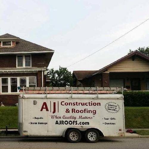 An AJ Construction & Roofing Trailer Outside a Home.
